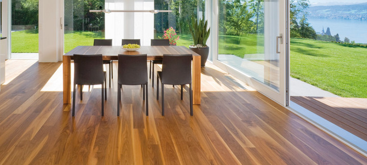 Die Küche ist mit massivem Boden ausgelegt. In der Mitte steht ein massiver Tisch mit Stühlen, und durch die Glasfenster sieht man den Ausgang zur Terrasse und zum Garten.